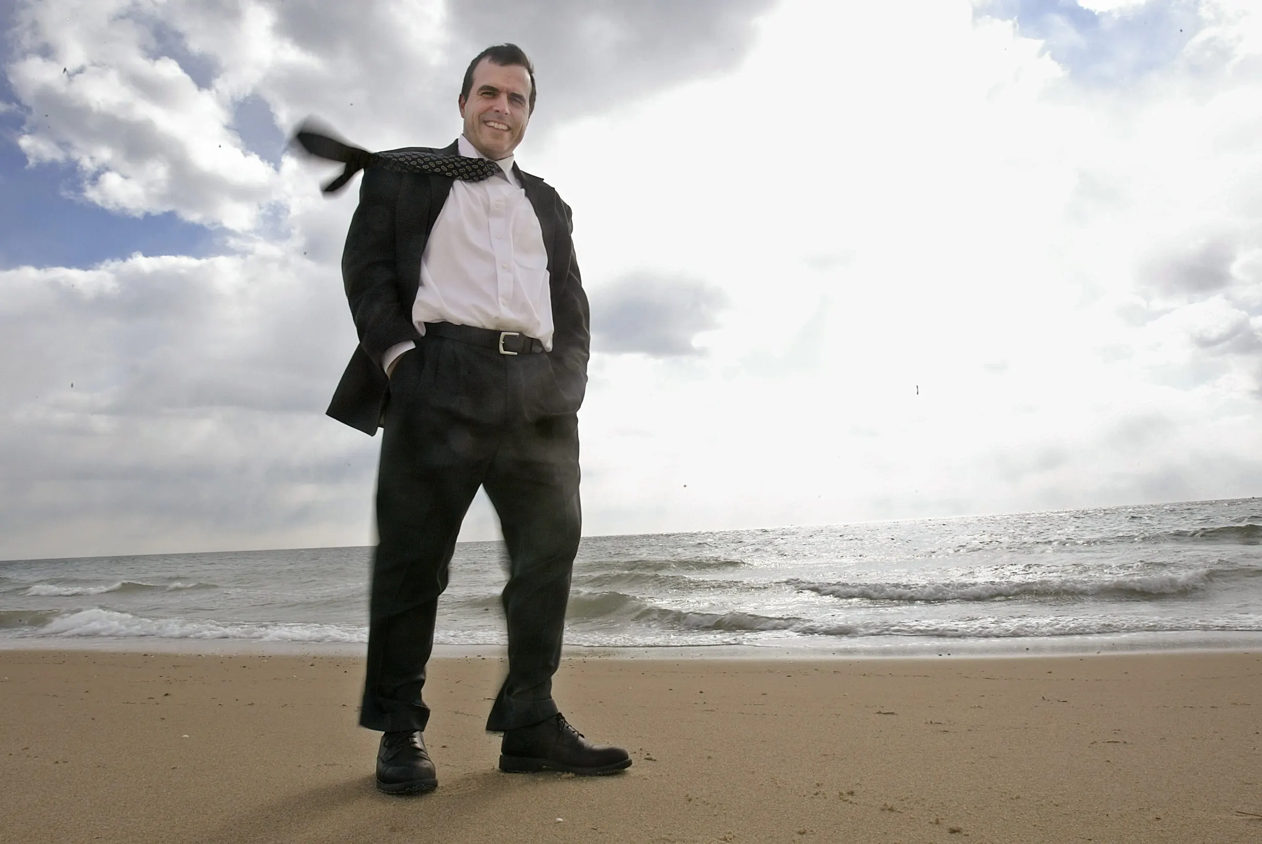 Not Windy Enough? — Mark Rogers, communication director for Cape Wind, an organization supporting the development of a wind farm on Horseshoe Shoal in Nantucket Sound, stands on a Cape Cod, Massachusetts, beach on Friday, February 4, 2006, overlooking the patch of water some 6.5 miles away where 130 wind turbines would be constructed. A move to limit the placement of offshore wind turbines has been placed in front of a U.S. House of Representatives conference committee as an amendment to an $8.7 billion Coast Guard Bill. Opponents contend the construction of a wind farm on Horseshoe Shoal is unwarranted because there is not enough wind in the area to power the turbines.  (AP Photo/Stephan Savoia)  © The Associated Press