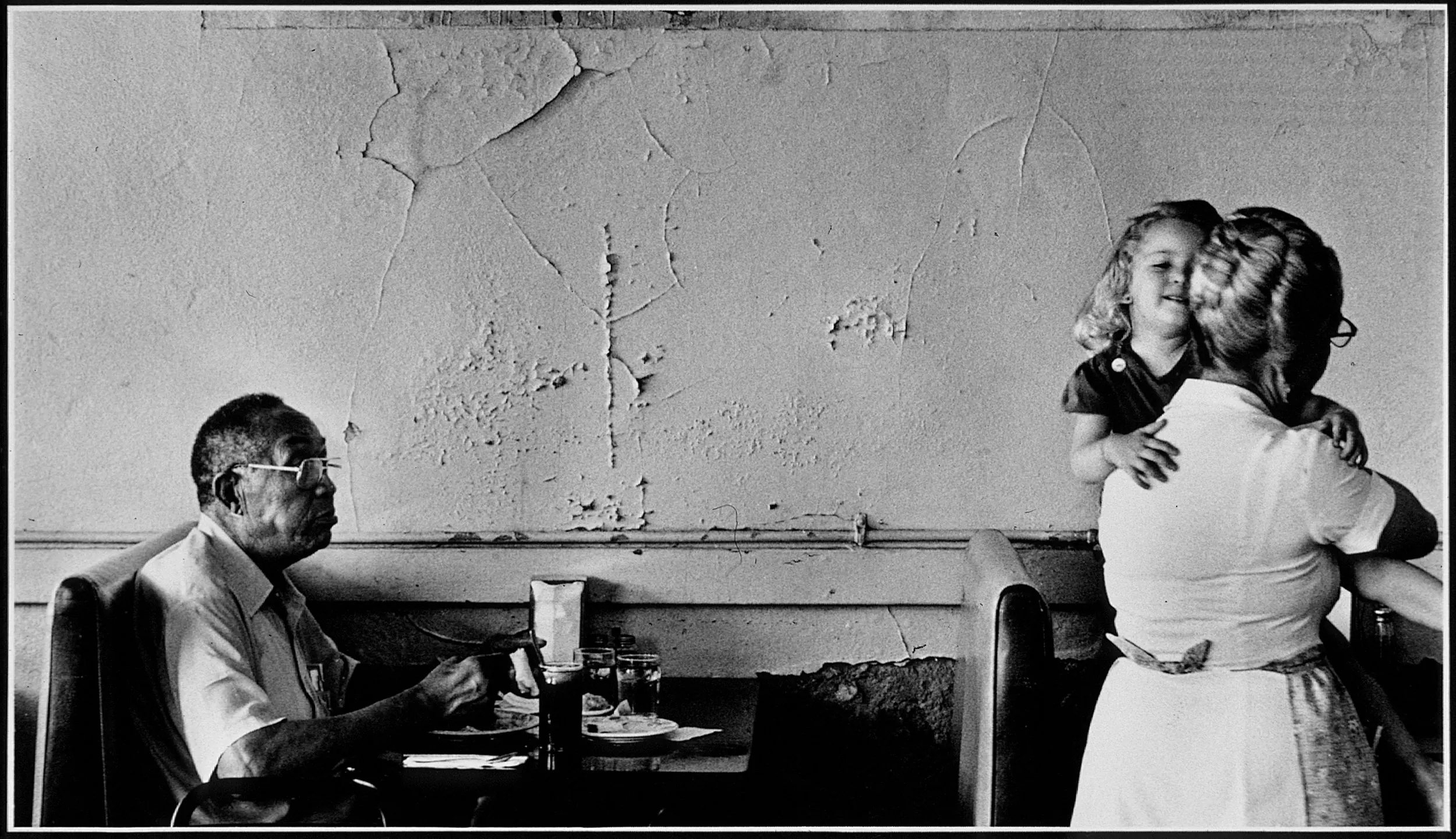 Lunch at Mae's Cafe — Waitress Norma Jean Rainford whisks away Mae's great-granddaughter, Marisa, as James Barron begins his lunch of red beans and rice, stew, dumplings and cornbread at Mae’s Cafe in rural southeast Louisiana.  (Photo by Stephan Savoia)  Published by The Baton Rouge Louisiana State-Times & Morning Advocate on July 3, 1987