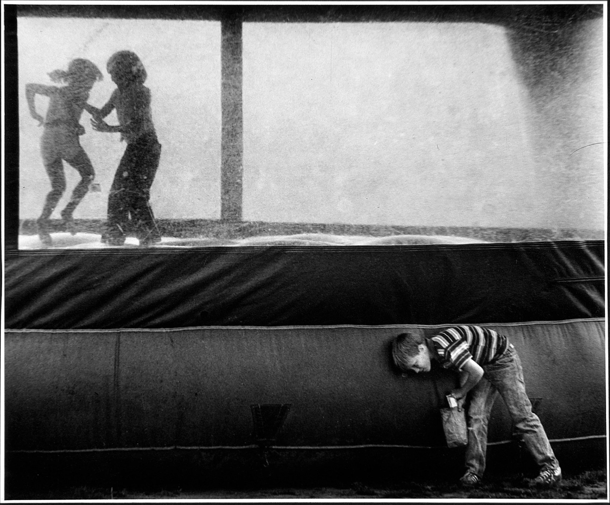 Bouncing Sound — A young boy listens to the sounds created by moving air as two friends bounce inside a inflatable moon-walk balloon in Louisiana.  (Photo by Stephan Savoia)  Published by The Monroe News-Star-World Circa 1983